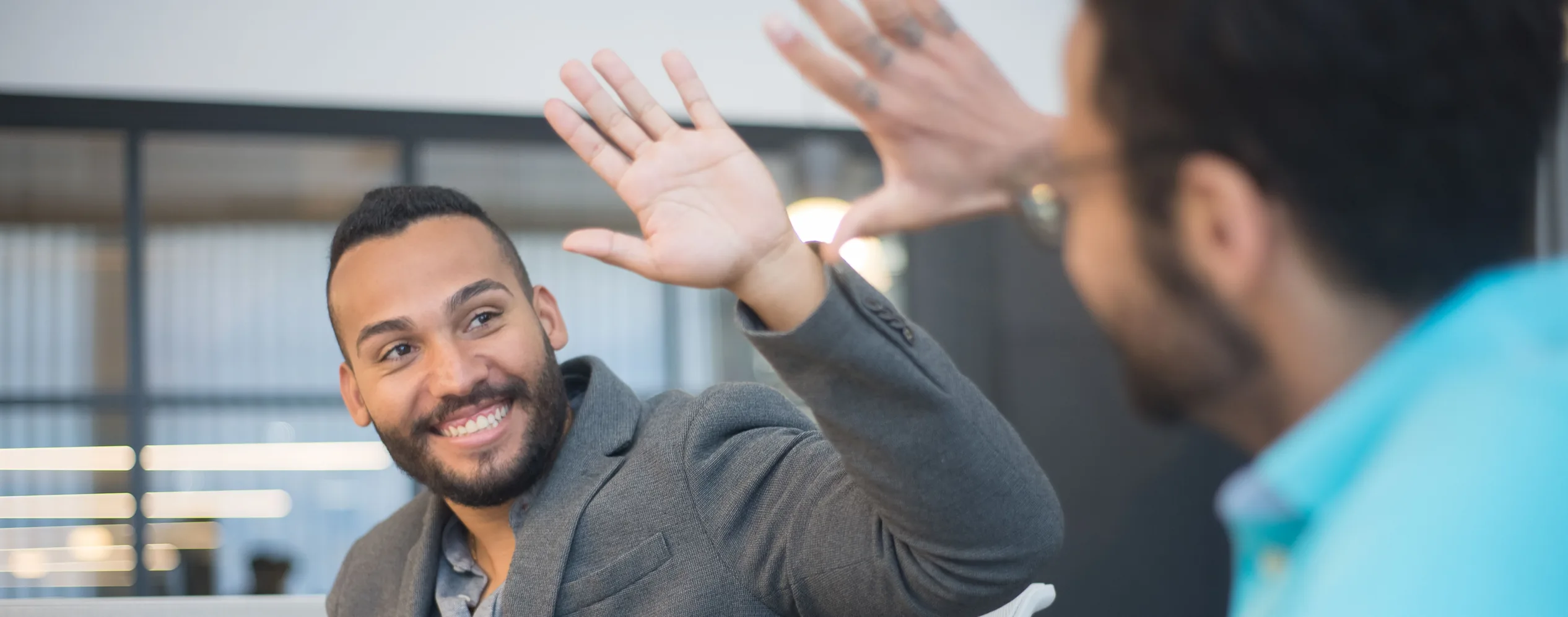 Two colleagues high-fiving across a desk